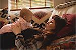 Mother playing with her baby on sofa in living room