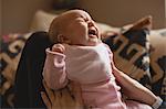 Close-up of mother consoling her crying baby in living room at home