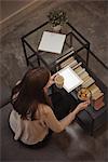 Woman with digital tablet having breakfast in living room at home