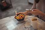 Close-up of woman using mobile phone while having breakfast at home