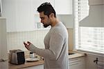 Man using mobile phone in kitchen at home