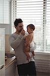 Father feeding his baby in kitchen at home