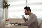 Man using laptop while having coffee at home
