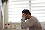 Stressed man sitting with hands on head at home