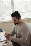 Handsome man writing on sticky note at home