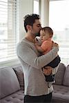 Father kissing his baby in living room at home