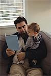 Father reading a book while holding his baby at home