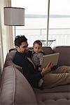 Father using digital tablet while holding his baby at home