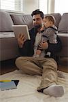 Father holding his baby while using digital tablet at home