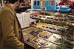Man looking at desserts on display at the dessert counter in the supermarket