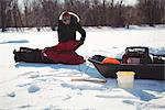 Ice fisherman assembling his tent in snowy landscape