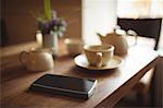 Mobile phone and coffee cup on wooden table in café