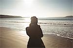 Rear view of woman standing on beach during day