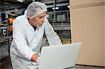 Serious male worker using laptop in cold drink factory