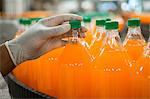 Close up of hand lifting bottles of juice to examine