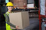 Portrait of beautiful female worker carrying box in warehouse