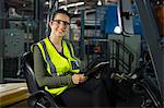 Portrait of beautiful female worker with digital tablet in forklift at warehouse