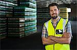 Portrait of confident male worker with arms crossed standing in warehouse