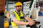 Portrait of young male worker driving forklift in warehouse