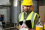 Thoughtful male worker using digital tablet in juice factory