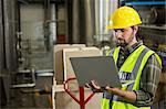 Serious male worker using laptop in distribution warehouse