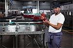 Portrait of young worker inspecting juice bottle at factory