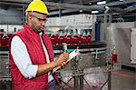 Serious male employee noting about products in juice factory