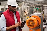 Confident male employee using digital tablet in juice factory