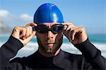 Athlete wearing swimming goggles at beach against sky