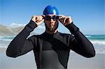 Athlete wearing swimming goggles by sea against sky