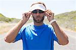 Confident male athlete wearing sunglasses on road