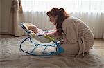 Side view of mother with baby in rocking chair at home