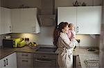 Caring mother with baby standing in domestic kitchen