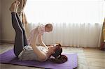 Full length of mother carrying baby while lying on exercise mat at home