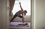 Fit mother exercising while looking at baby on yoga mat at home