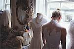 Rear view of young bride in white wedding dress in a boutique
