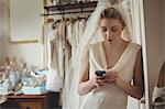 Young bride using mobile phone in a boutique