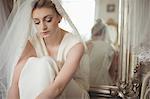 Thoughtful young bride in a white dress relaxing in boutique