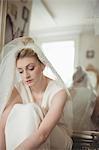 Thoughtful young bride in a white dress relaxing in boutique