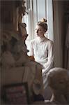 Thoughtful young bride looking through window in a boutique