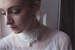 Thoughtful young bride standing near window in a boutique