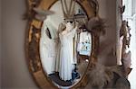 Reflection of bride selecting wedding dress from clothes hanger in the mirror at boutique