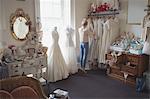 Young woman selecting wedding dress from clothes hanger in a boutique