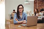 Female executive sitting with arms crossed at desk in office