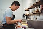 Side view of male chef adding chopped carrot into bowl in commercial kitchen