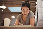 Young female barista using digital tablet in coffee shop