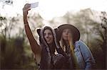 Female friends talking selfie on mobile phone in forest