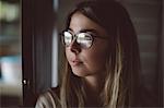 Close-up of beautiful woman looking through window at home