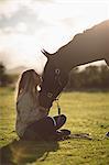 Woman petting horse in farm on a sunny day