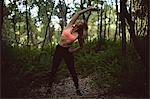 Beautiful woman performing stretching exercise in forest